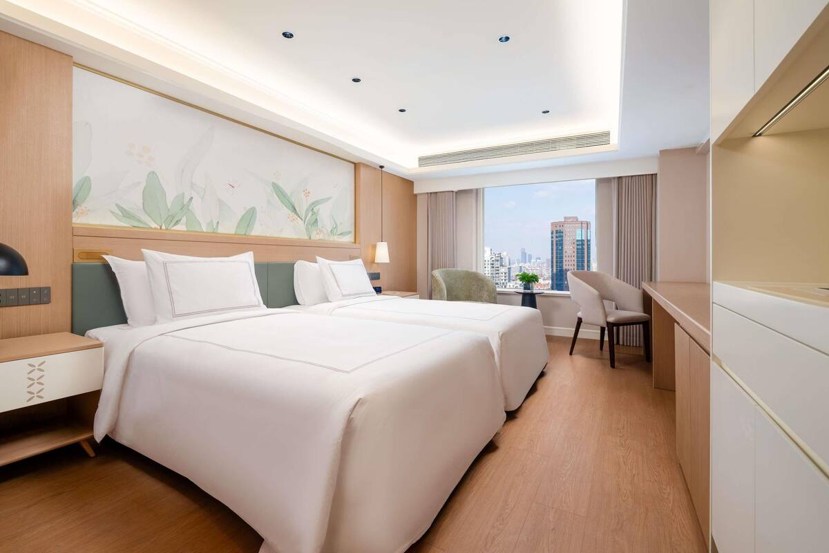 Camera d'albergo con un letto grande, una scrivania e vista sulla città.