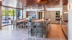 Una cocina moderna con una isla grande, taburetes de bar y una zona de comedor con mesa y sillas.