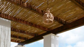 Eine Terrasse im Freien mit Holzboden, weißen Säulen und einer hängenden Lampe.