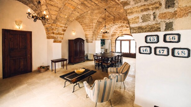 Ein geräumiger Raum mit hoher, gewölbter Stein Decke, einem Essbereich mit Holztisch und Stühlen sowie einer Wand mit beschrifteten Plaketten.
