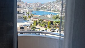 En utsikt från en balkong med utsikt över en kuststad med byggnader, en småbåtshamn och ett hotell som heter ”Mediterranean”.