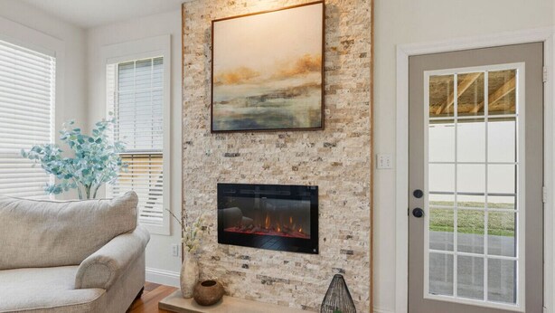 A living room with a fireplace, a couch, and a door with a view. - Emily House | 3 King Beds | Pet Friendly (Ada)