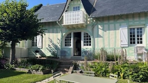 Una casa con un balcone, un ingresso e un piccolo giardino con tavolo e sedie.