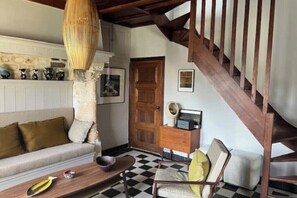 A living room with a checkered floor, a wooden staircase, a sofa, a coffee table, and a chair.