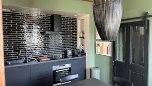Una cucina moderna con zoccolo a mattoni neri, forno integrato e zona pranzo con tavolo e sedie.