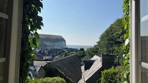 Vista di un borgo costiero attraverso una finestra con vista su una scogliera e il mare.