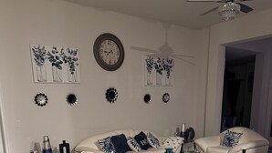 A modern living room with a sofa set, coffee table, decorative wall art, and a ceiling fan. - 3-bedroom house in beautiful Port Charlotte with cool vibes (Port Charlotte)