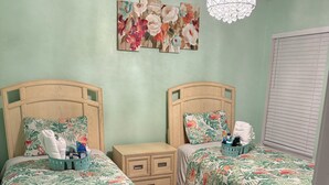 A bedroom with two beds, a ceiling fan, a chandelier, and a floral painting on the wall. - 3-bedroom house in beautiful Port Charlotte with cool vibes (Port Charlotte)