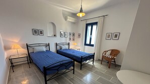 Une chambre avec deux lits, une chaise, une table et une fenêtre avec des rideaux.