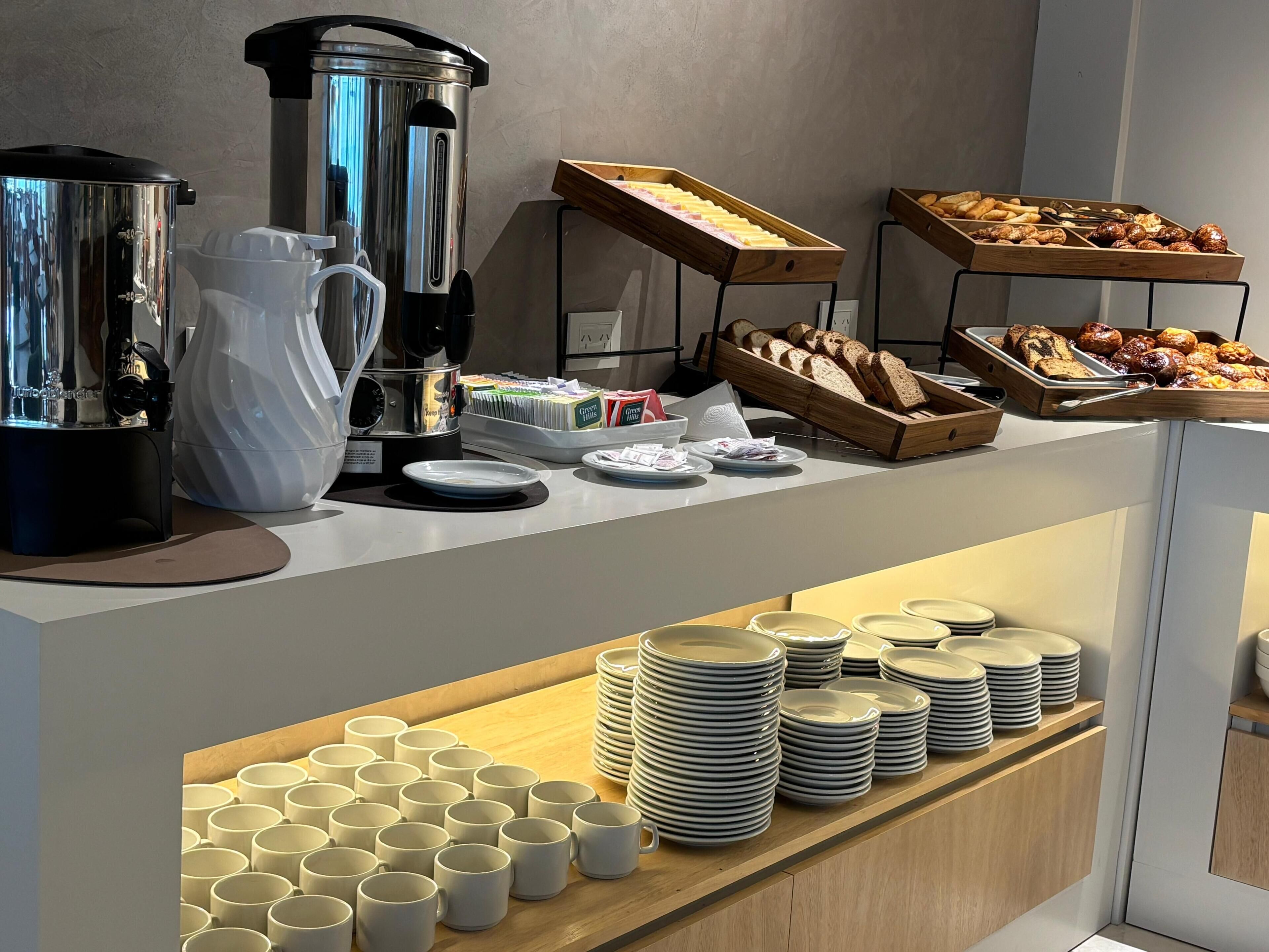 Een buffetopstelling met een koffiezetapparaat, een waterdispenser en diverse etenswaren.