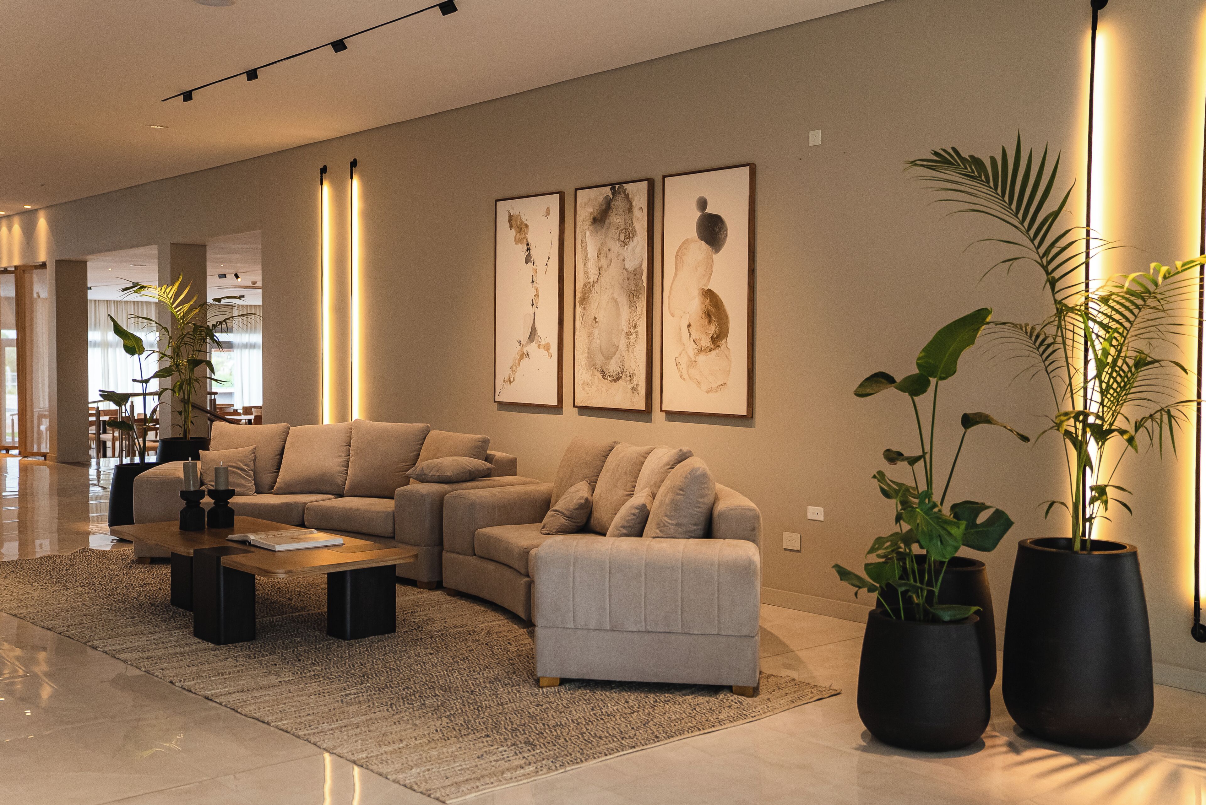 Una sala moderna con un sofá seccional, una mesa de centro y dos plantas en macetas.