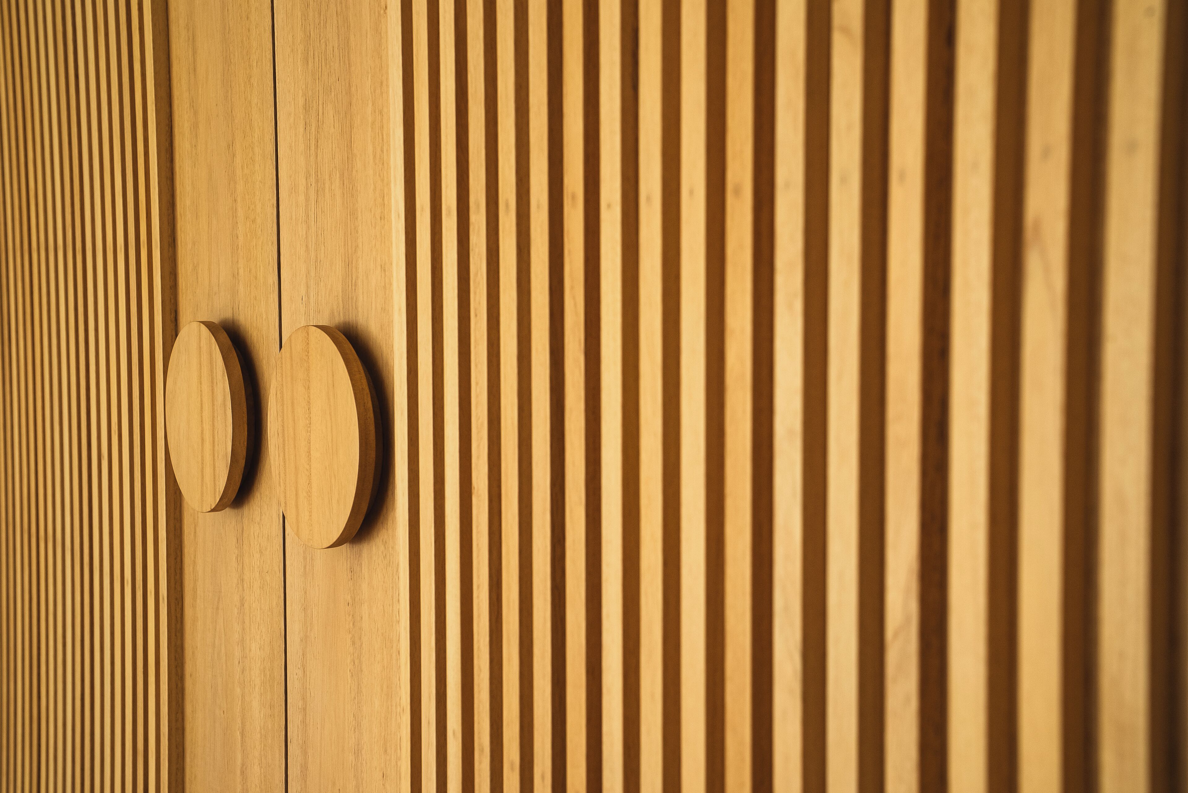 Un panel de madera con ranuras verticales y dos pomos redondos.