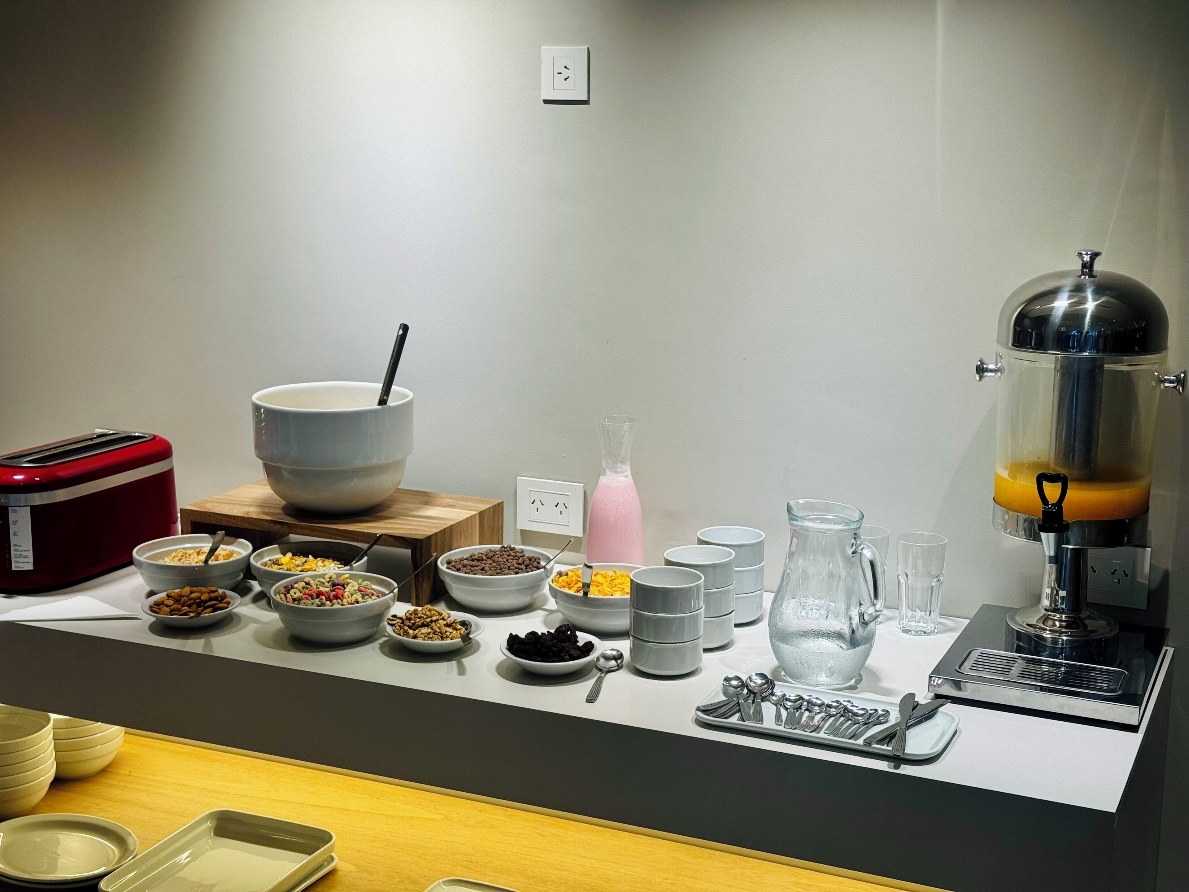A breakfast buffet setup with various food items, a juicer, and a toaster.