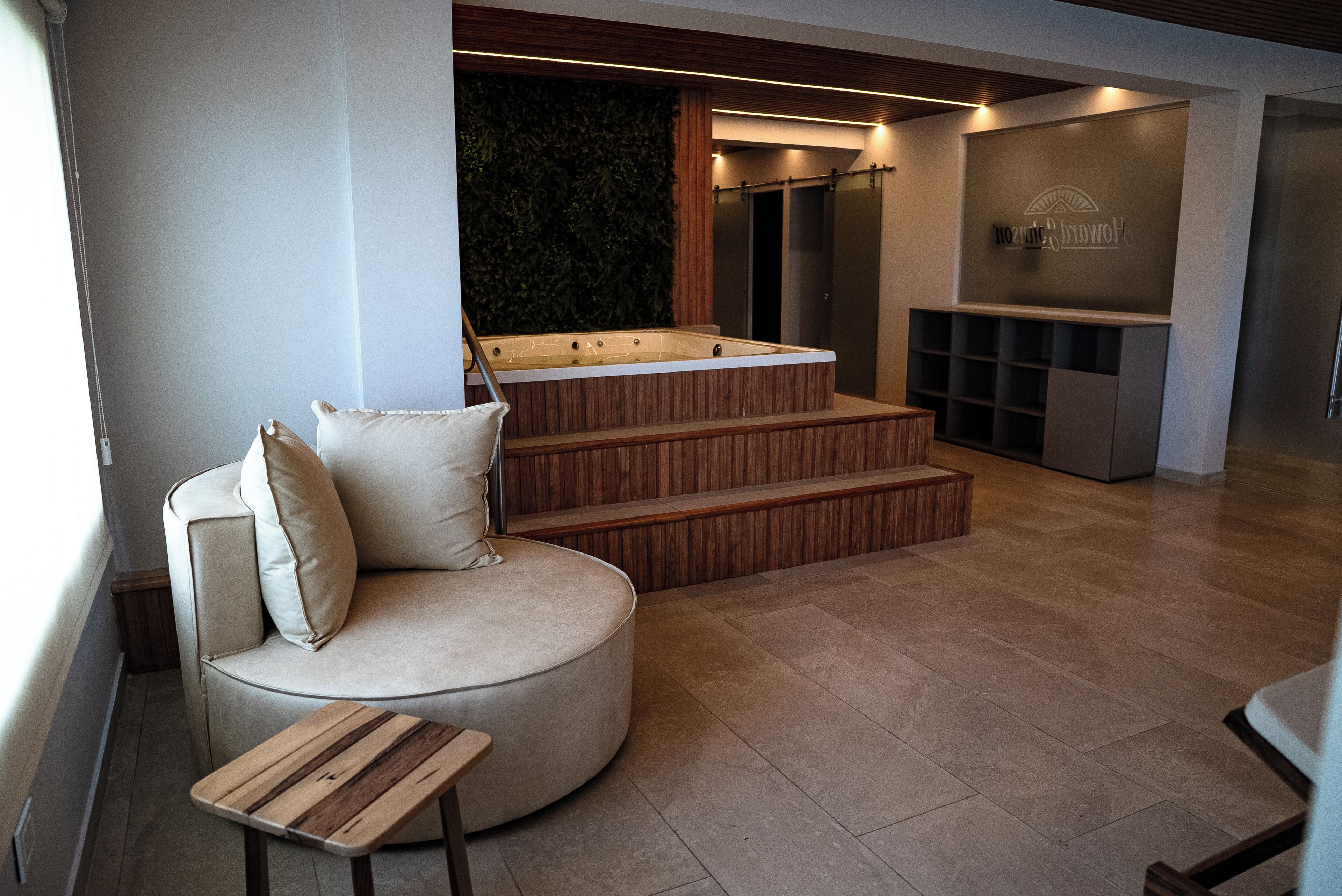 Un interno moderno con un divano curvo, una panca in legno e una zona idromassaggio.
