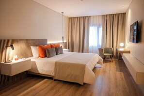 Una habitación de hotel moderna con una cama grande, mesitas de noche, un escritorio y una silla.