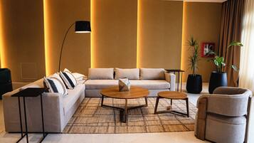 A modern living room with a sectional sofa, two round coffee tables, a floor lamp, and a potted plant.