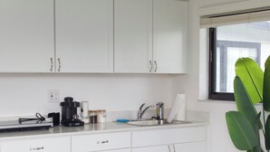 A kitchen with white cabinets, a coffee maker, and a plant. - Cozy Studio Near Hard Rock Stadium (Miami)