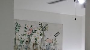 A bedroom with a bed, pillows, a headboard, a wall-mounted painting of flowers, and a bedside lamp. - Cozy Studio Near Hard Rock Stadium (Miami)
