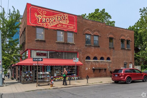 A brick building with a red awning labeled 'Prospero's Books & Media,' a fire hydrant, and a red SUV parked on the street. - Your Kansas City World Cup Base – Walkable, Private, BUDGET June 12-July 13 only (Kansas City)