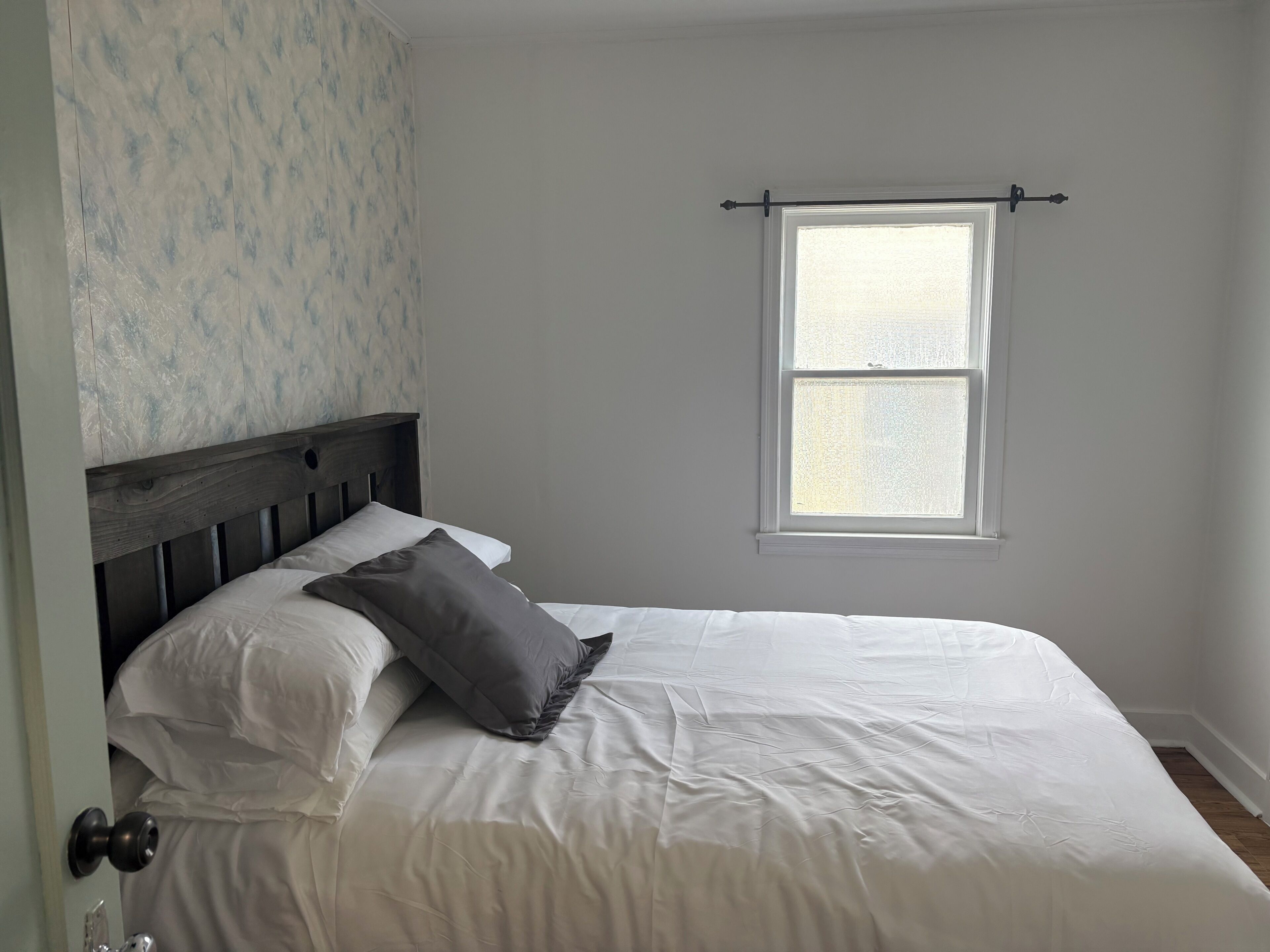 Un dormitorio con cama, ventana y puerta.