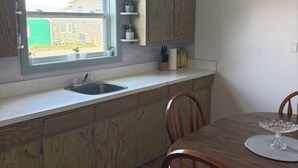 A kitchen with wooden cabinets, a window, a sink, and a dining table with chairs.