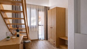 A room with a wooden desk, a wine bottle, a wine glass, a ladder, and a wardrobe. - Hotel Soran (San Lorenzo Dorsino)