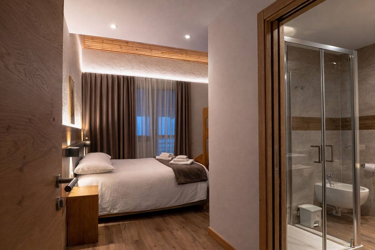 Un dormitorio moderno con cama, mesita de noche y zona de ducha con vidrio.