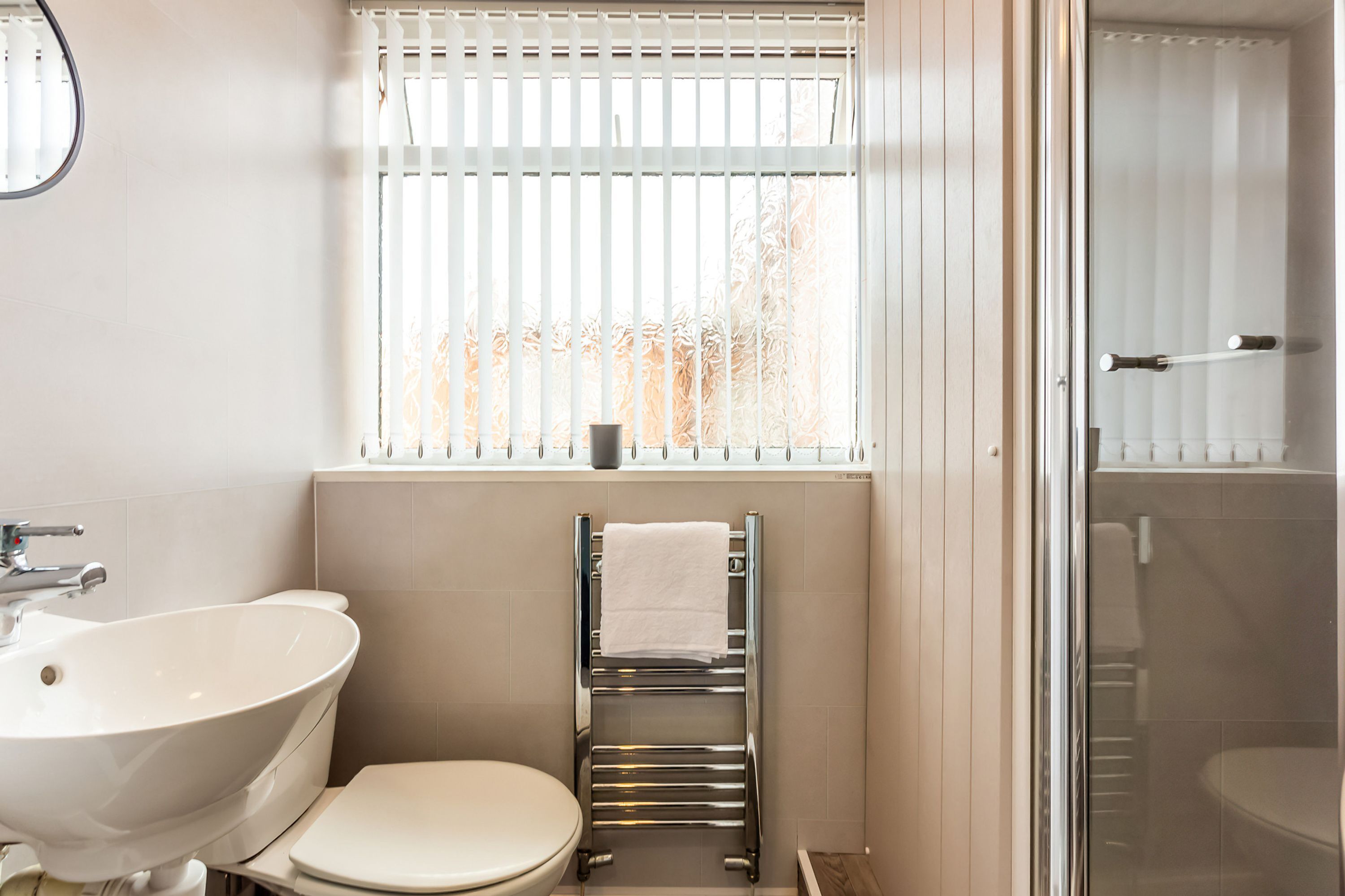 A bathroom with a white sink, toilet, and towel rack.