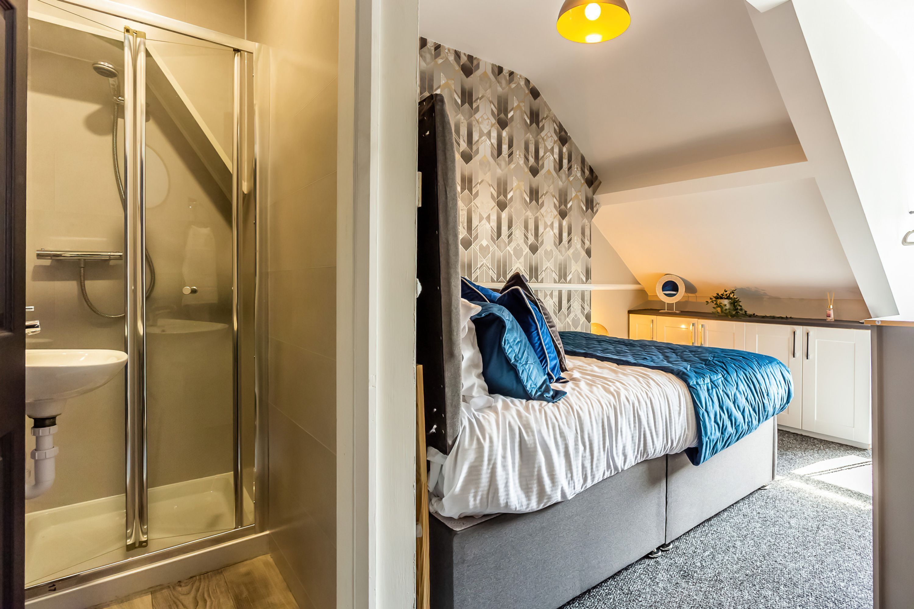 A bedroom with a bed, a shower, and a white sink.