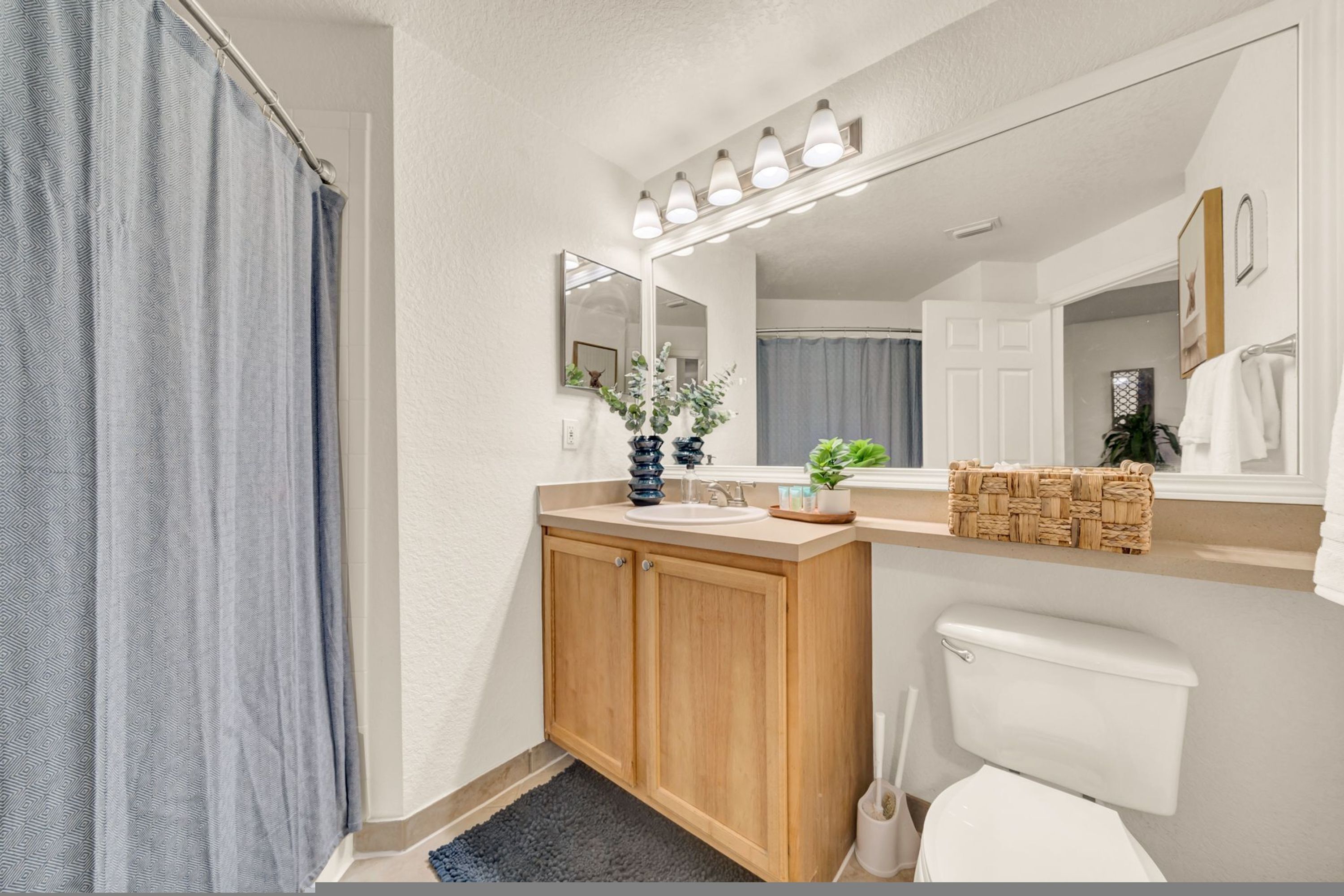 A bathroom with a wooden vanity, a sink, a mirror, and a toilet.