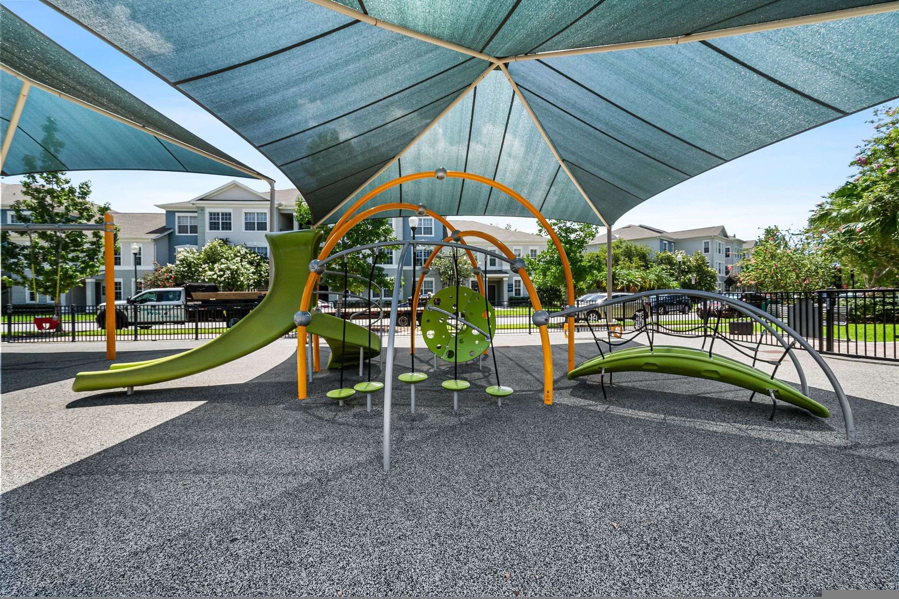 A playground with a canopy, slides, and swings.