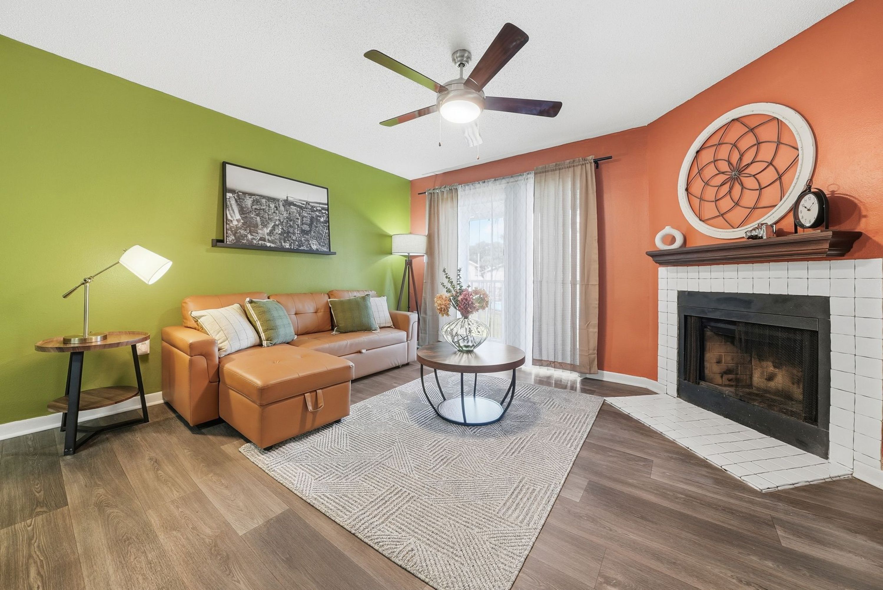 Ein Wohnzimmer mit einer Couch, einem Couchtisch, einem Kamin und einem Deckenventilator.