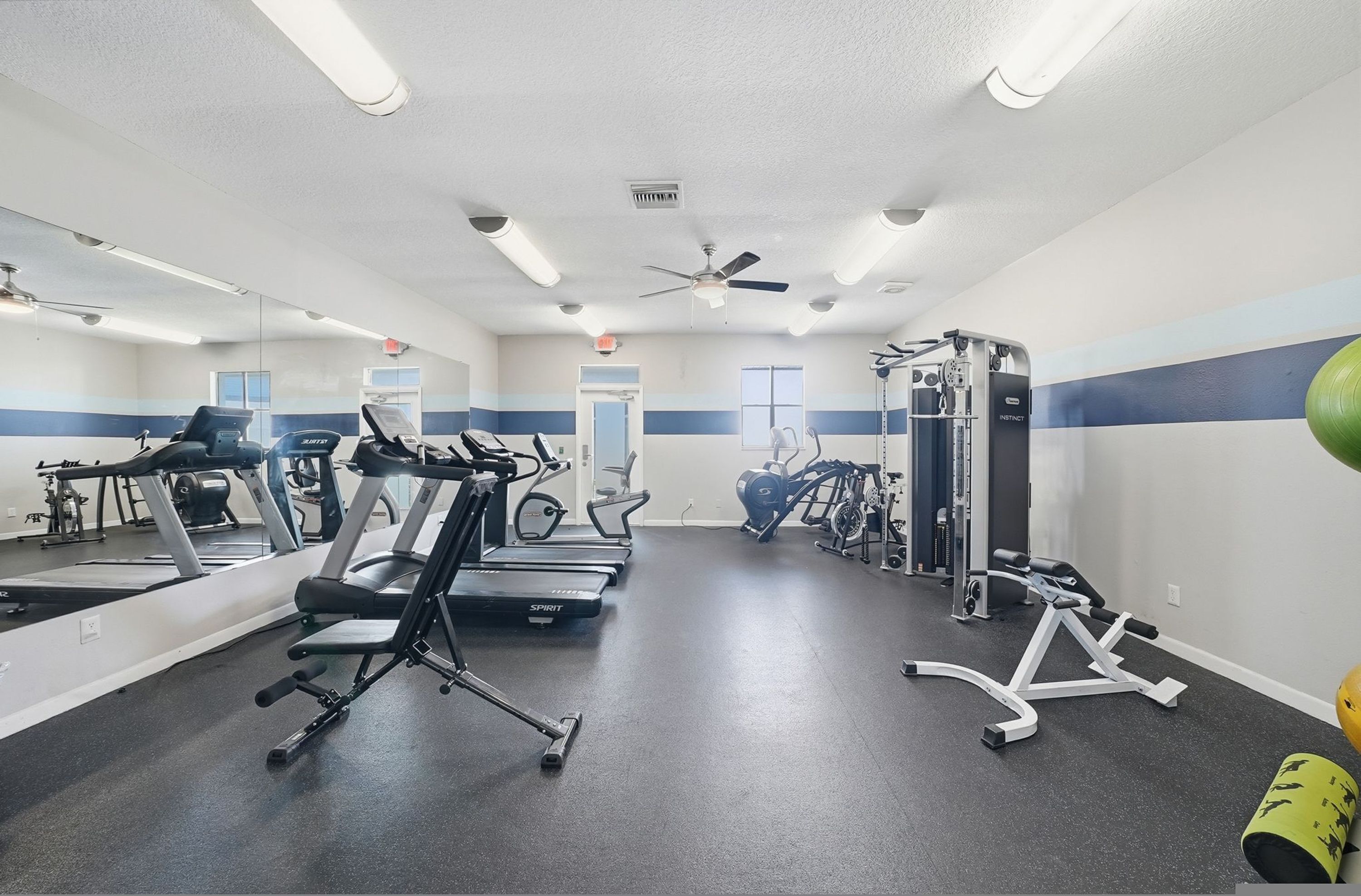 A gym with treadmills, elliptical machines, and weightlifting equipment.