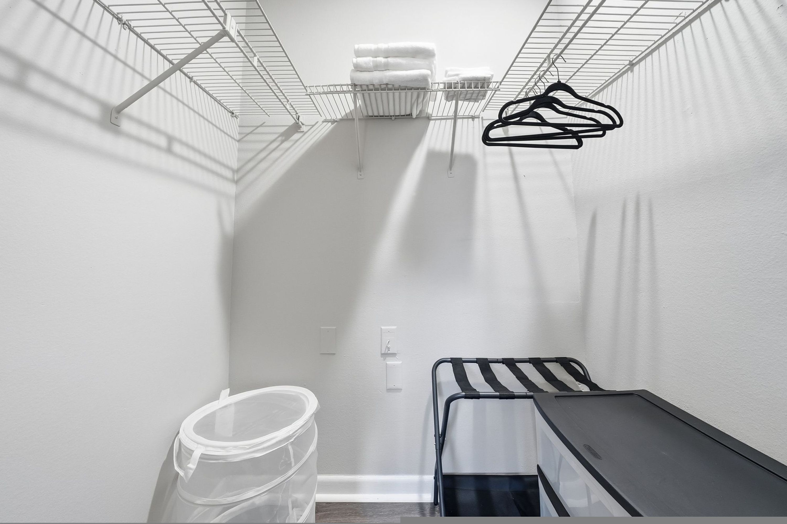 A compact storage area with metal shelves, a plastic container, and a metal rack.