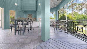 A covered outdoor area with a dining table and chairs, a ceiling fan, and a view of trees through large windows. - Vibrant 2BR 2BA w King Bed Pool Gym 11 (Tampa)