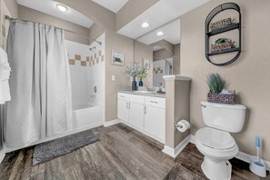 A bathroom with a shower, toilet, and sink, with wooden flooring and beige walls. - Vibrant 2BR 2BA w King Bed Pool Gym 11 (Tampa)