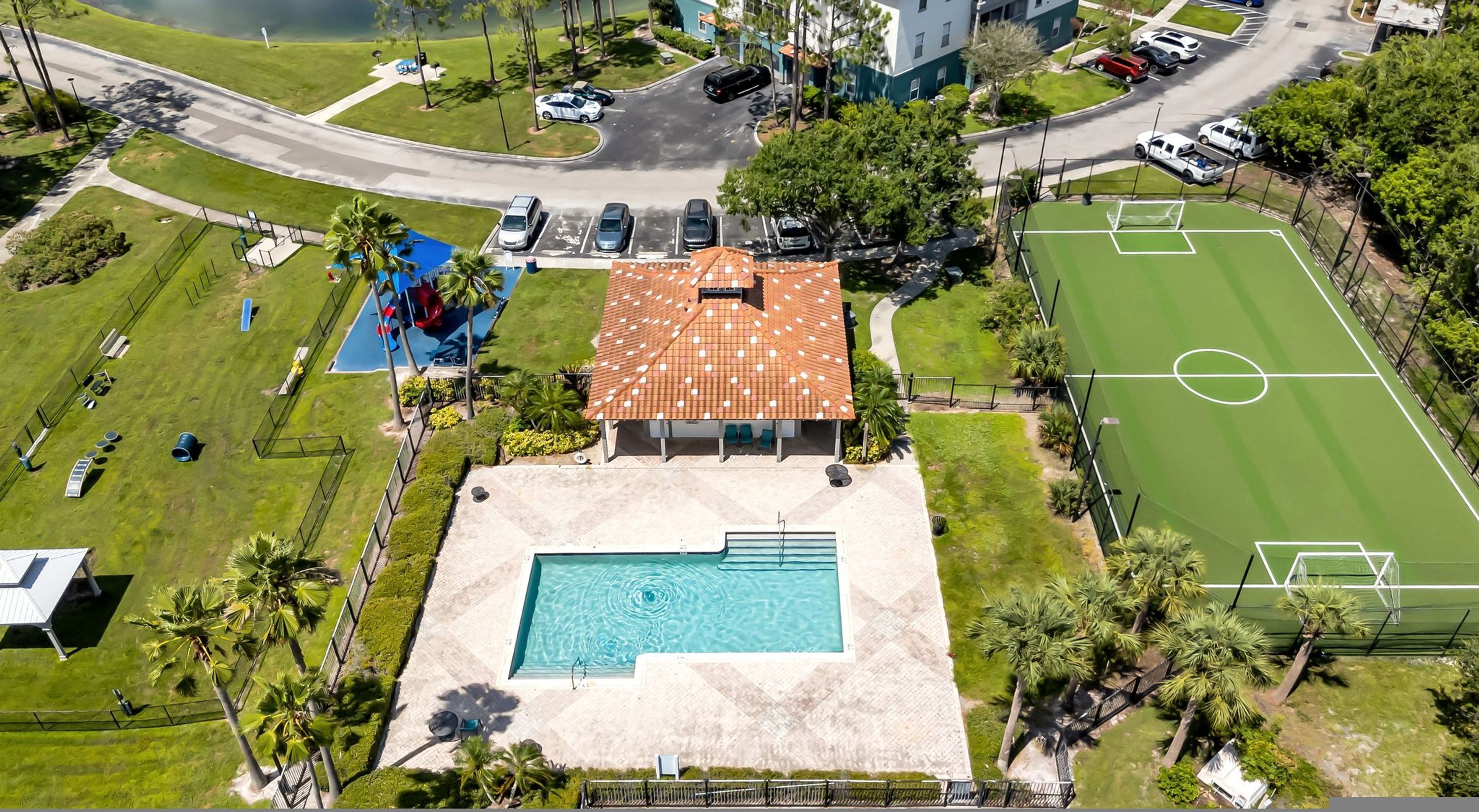 Vista aérea de una propiedad con piscina, cancha de tenis y un edificio con techo de tejas.