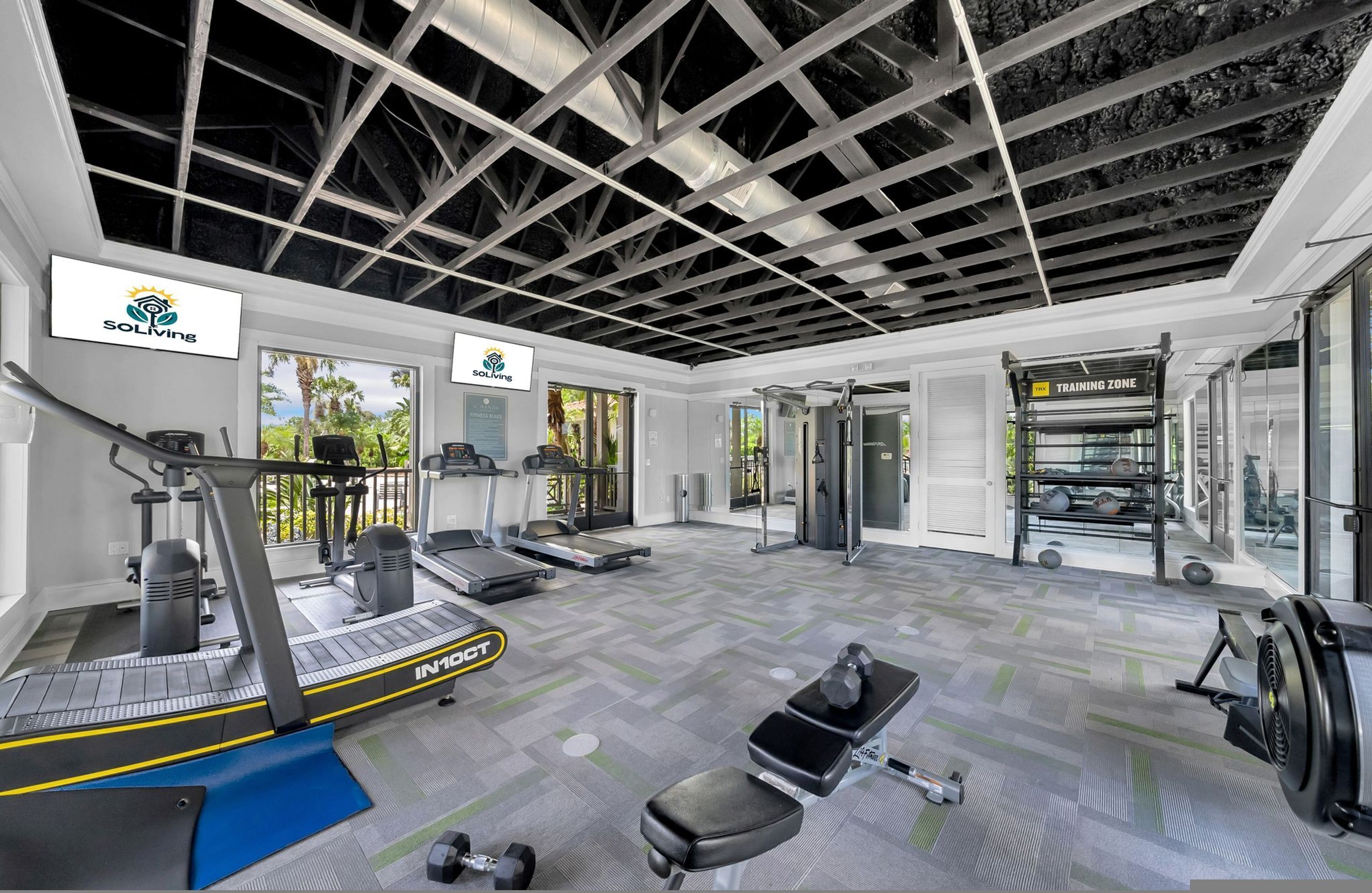 A gym with treadmills, weights, and a ceiling with a grid pattern.