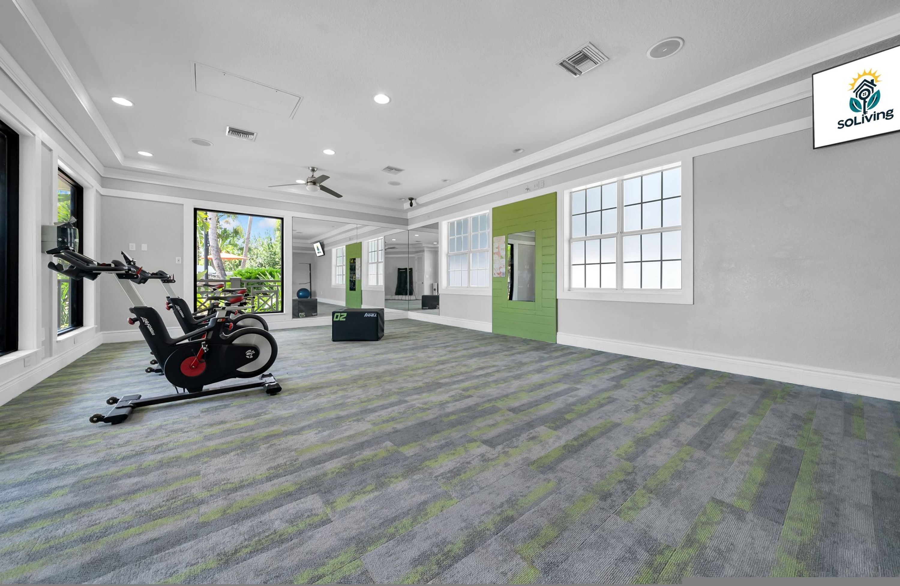 A spacious room with a stationary bike, a treadmill, and a large window.