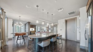 A modern kitchen with a large island, bar stools, pendant lighting, and a refrigerator. - Stylish 2BR w Pool Pet-friendly Unit 13 (Tampa)