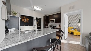 A modern kitchen with granite countertops, stainless steel appliances, and a dining area with a round table and chairs. - Stylish 2BR Corporate Stay Pool Balcony 2 (Tampa)