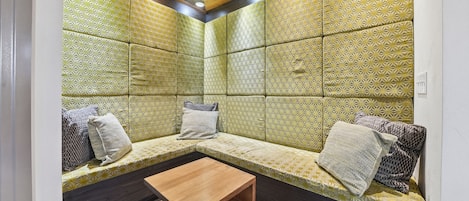 Ein Zimmer mit Sitzecke, einem Holztisch und Wandverkleidung mit Muster.