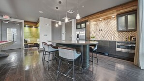 A modern kitchen with a central island, bar stools, and a herringbone-patterned backsplash. - Chic 2BR w Pool Pet-friendly Unit 14 (Tampa)