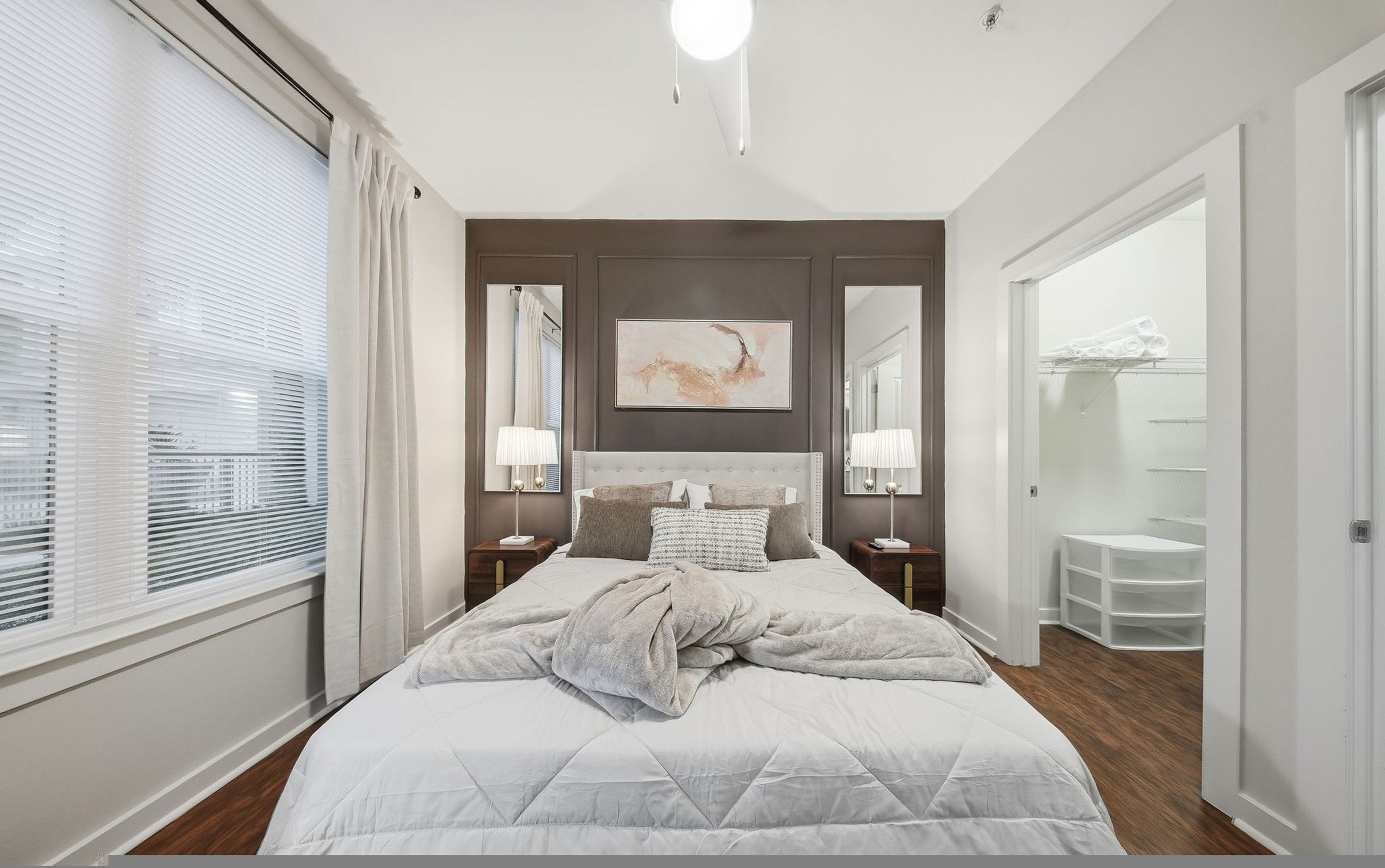 A modern bedroom with a large bed, bedside lamps, a mirror, and a painting on the wall.