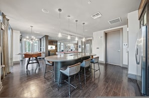 A modern kitchen with a central island, bar stools, pendant lighting, and a large refrigerator. - Chic 2BR w Pool Pet-friendly Unit 14 (Tampa)