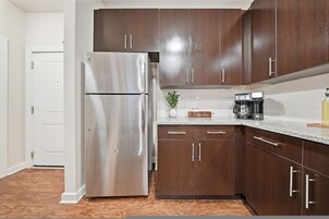 Una cocina con electrodomésticos de acero inoxidable, armarios de madera y una cafetera en la encimera.