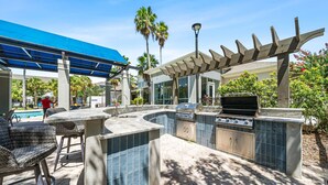 An outdoor kitchen with a grill, seating area, and a covered patio. - Stylish 2BR 2BA w Pool Gym Near Airport 3 (Tampa)
