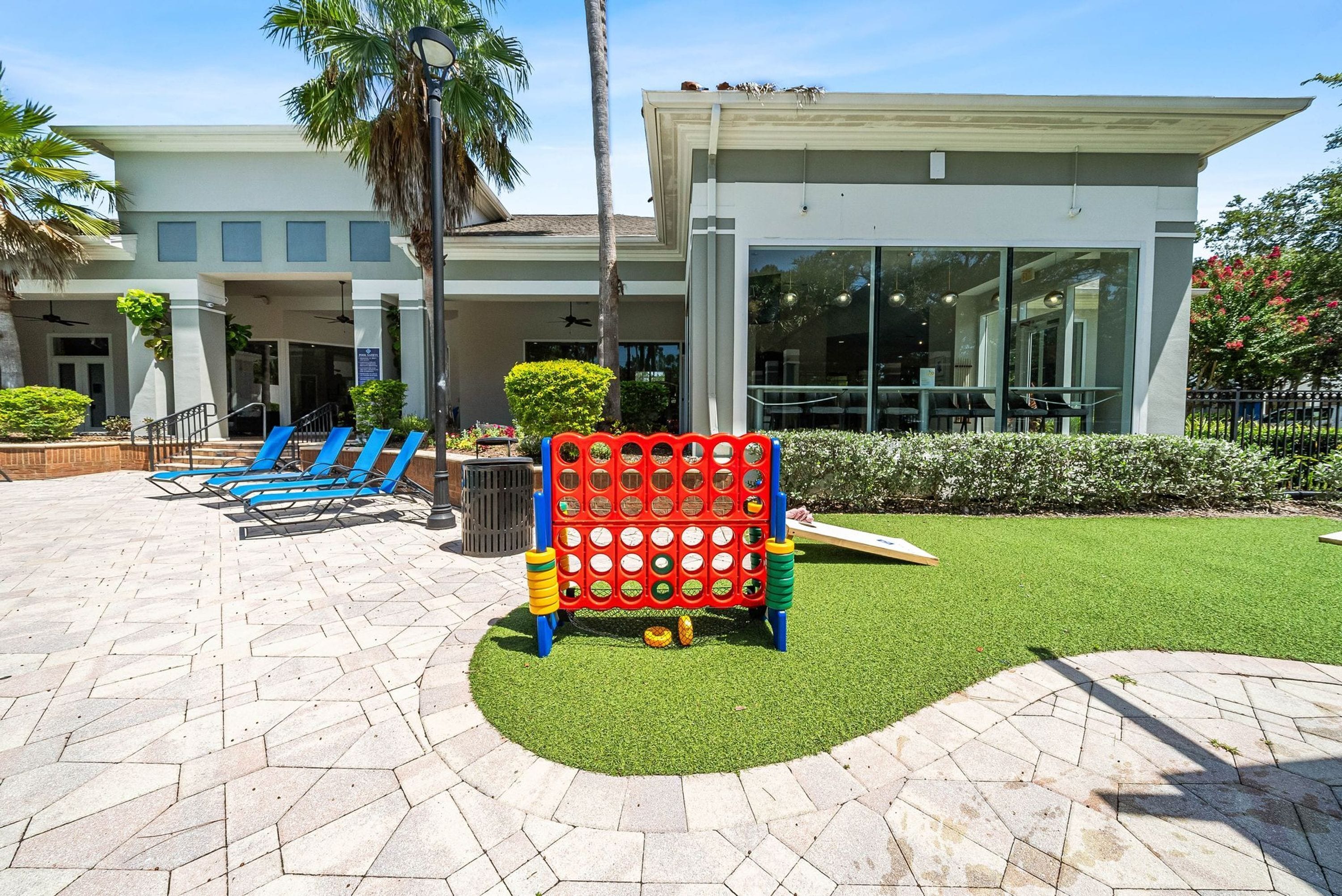 A modern building with a covered outdoor seating area, a children's play structure, and a well-maintained lawn.