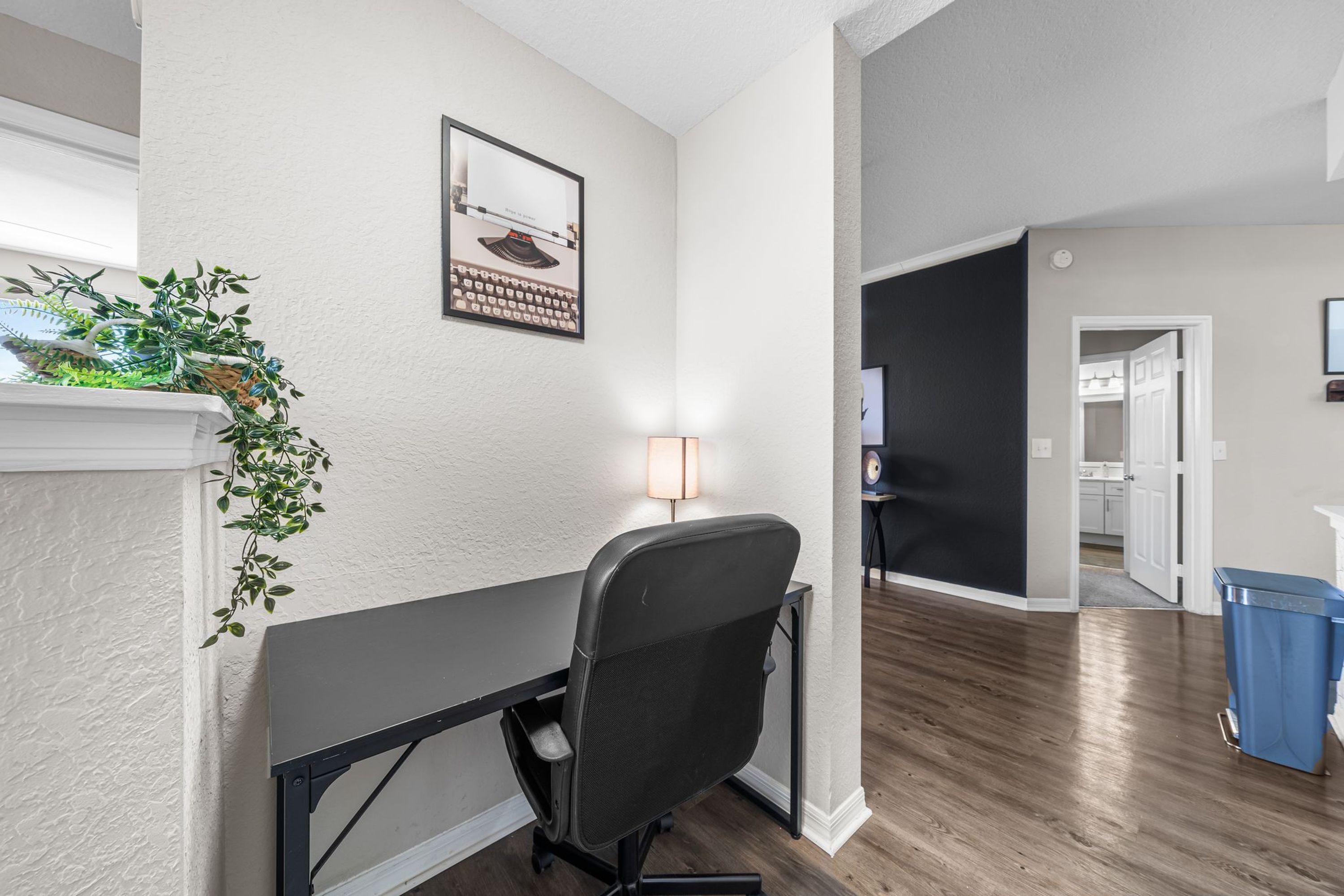 Un espacio de oficina moderno con un escritorio, una silla y un cuadro en la pared.