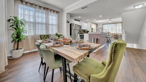 A dining area with a wooden table, green chairs, and a potted plant. - Modern 2BR 2BA Pool Gym Near Airport 8 (Tampa)